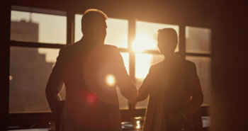 Business people, handshake in office for meeting welcome or onboarding with sunlight or lens flare. Corporate, silhouette and shaking hands in workplace for partnership, thank you or hiring deal